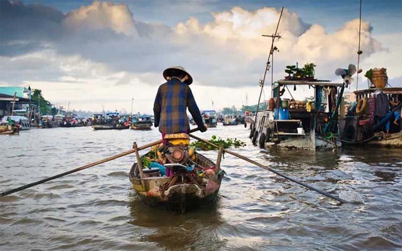 The Cai Be floating market with boats filled with fruits and goods, creating a lively atmosphere on the water.